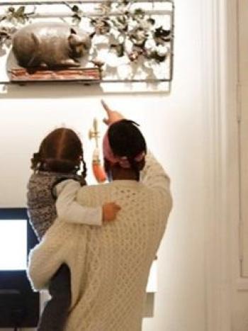 un parent montre pointe du doigt une enseigne à son enfant qu'il porte dans les bras